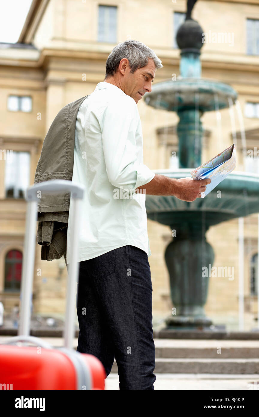 man in city street looking at map Stock Photo
