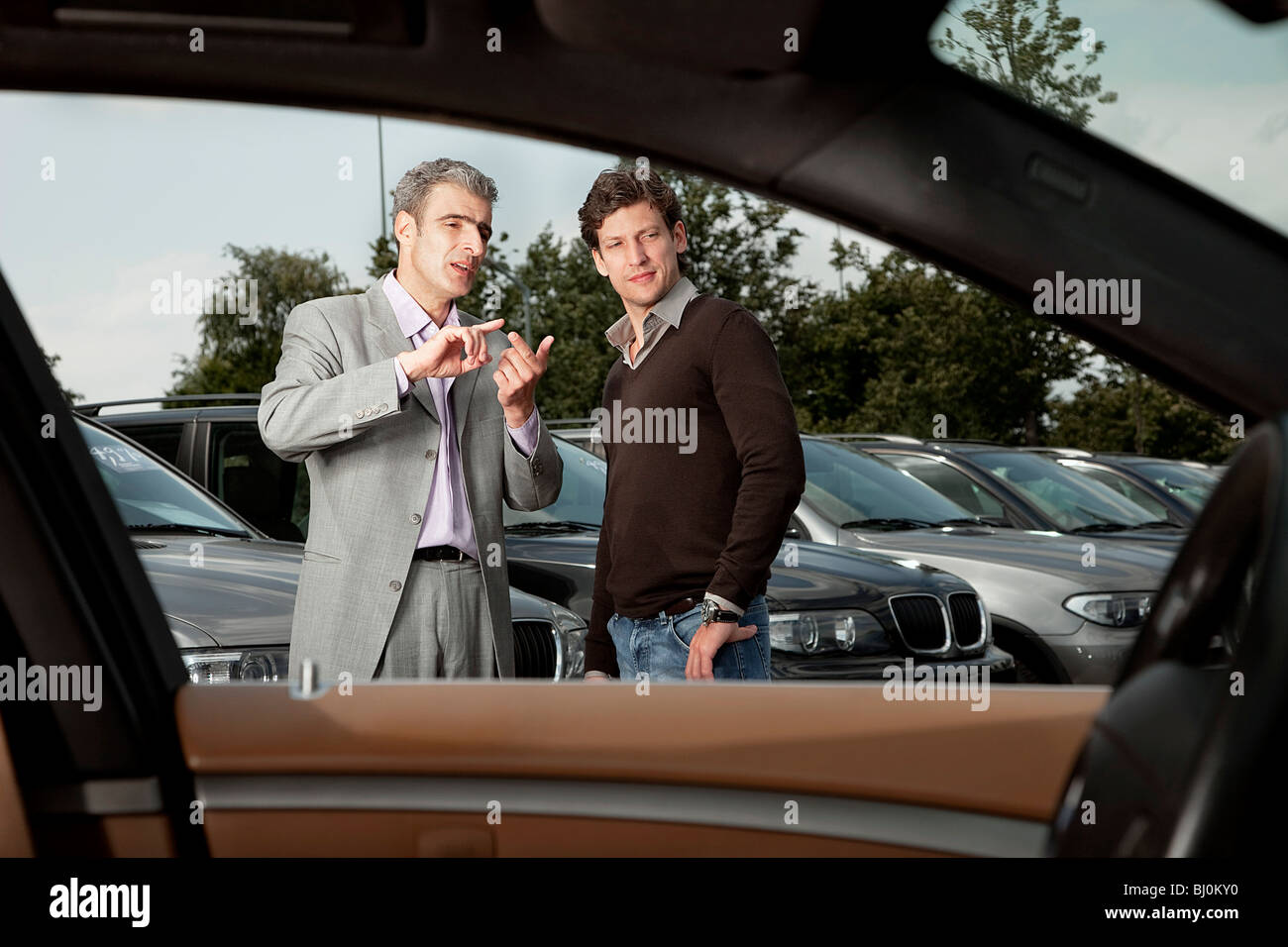 salesman and customer at car dealer having conversation Stock Photo