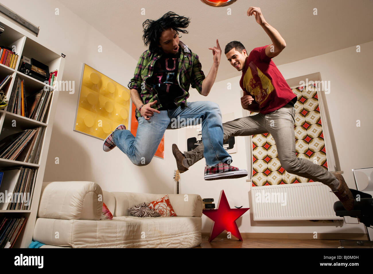 two young men at party playing air guitar Stock Photo