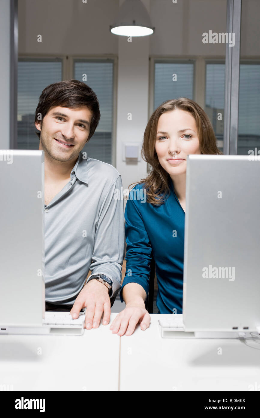 portrait of two business people sitting behind computers Stock Photo