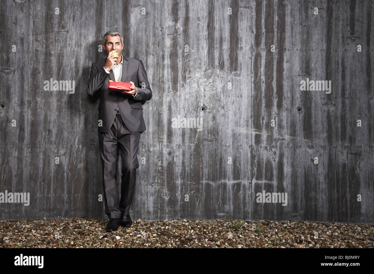 businessman holding box with fruits and eating apple Stock Photo