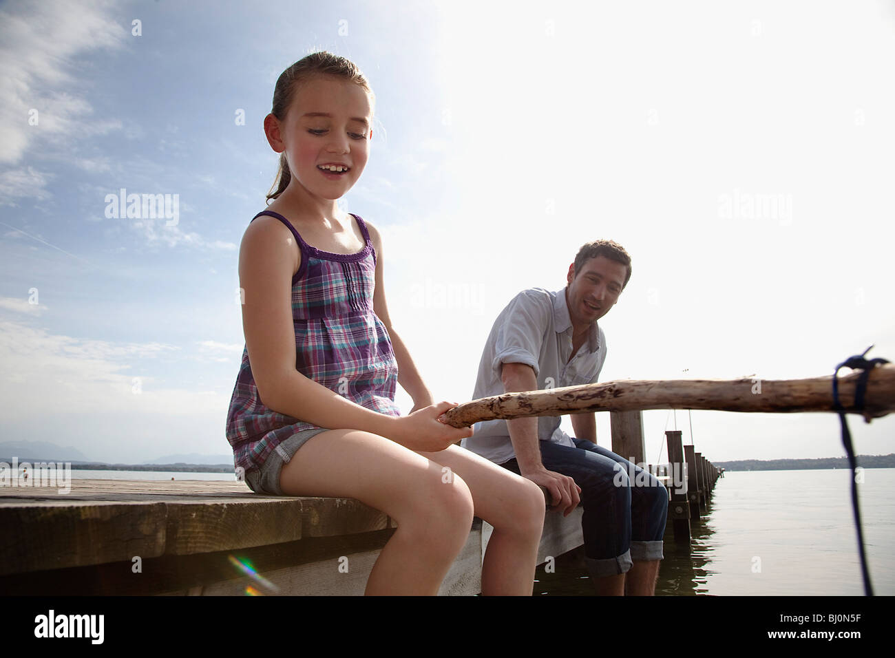 father and daughter on pier angling together Stock Photo