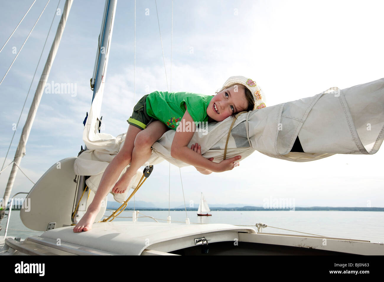 young girl lying on mast of sailing ship Stock Photo