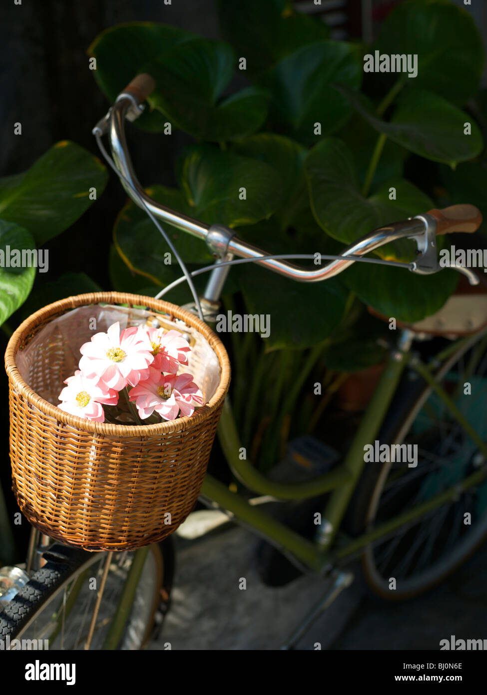 Wicker bicycle basket with fake pink flowers inside Stock Photo Alamy