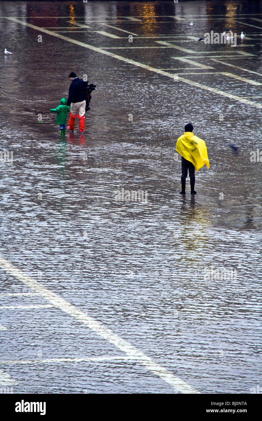 A family wading through the flooded Piazza San Marco in Venice, Veneto, Italy Stock Photo
