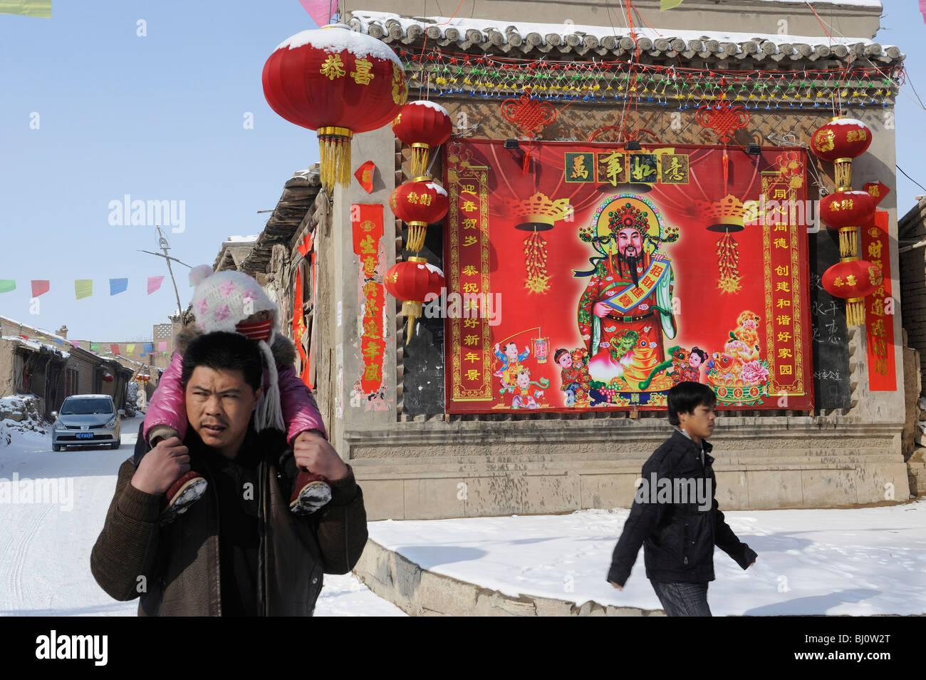 Villagers past a painting of the God of wealth on a wall during Chinese Spring Festival in Hebei province, China. 01-Mar-2010 Stock Photo