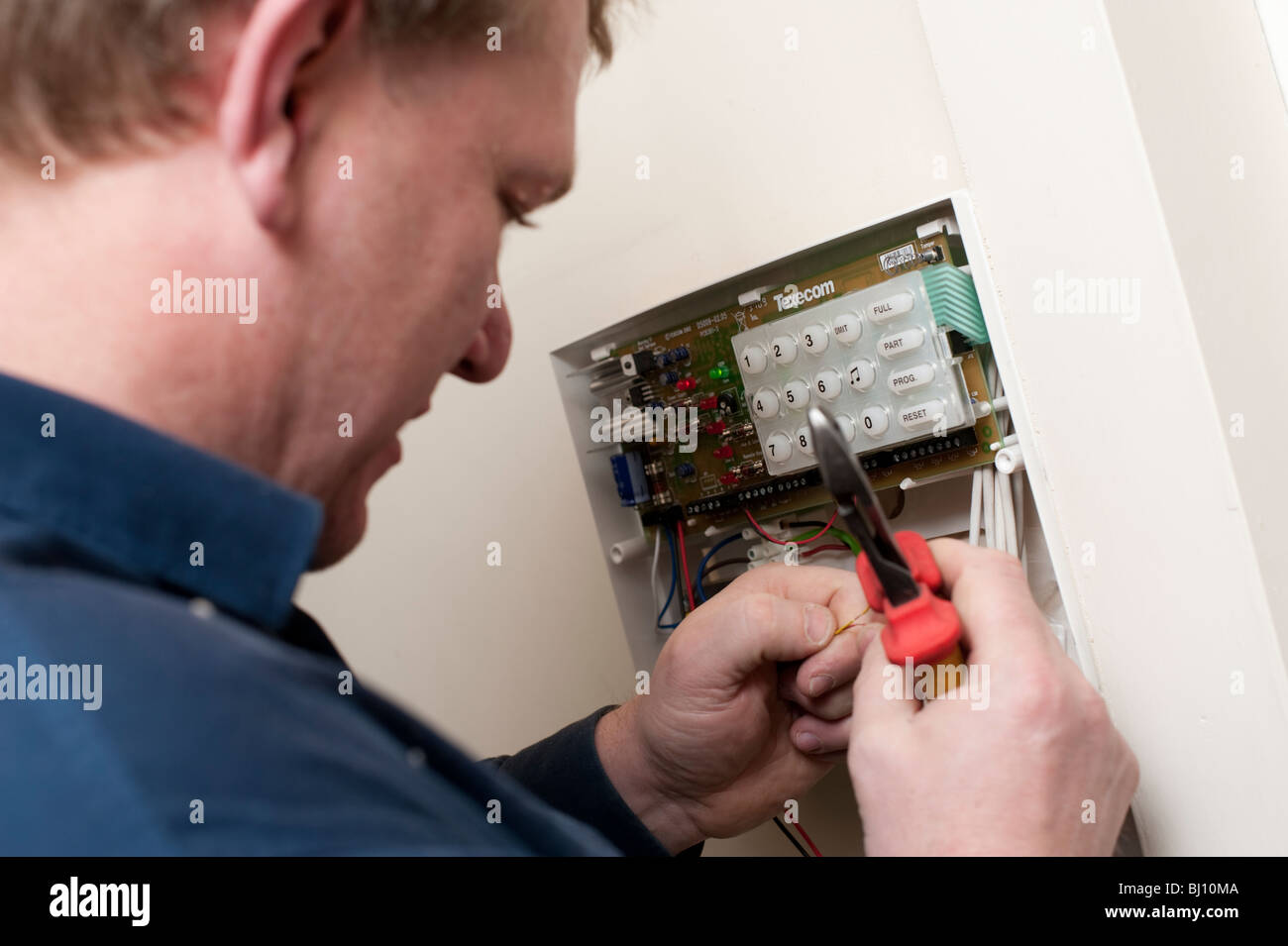 Electrician fitting a burglar alarm in a Shropshire home Stock Photo