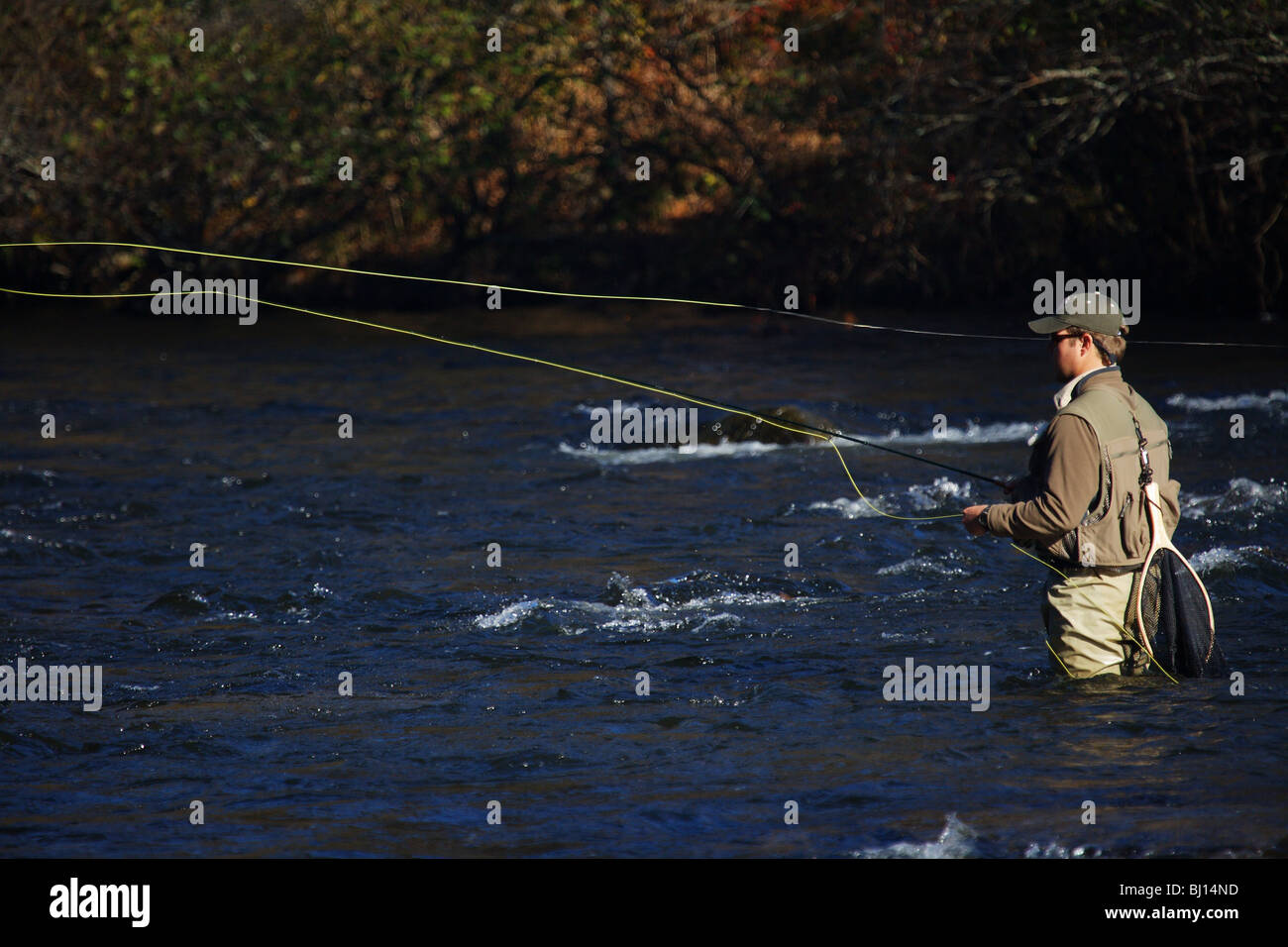 FLY FISHERMAN FISHING IN FAST RUNNING RIVER IN SEARCH OF TROUT TOCCOA