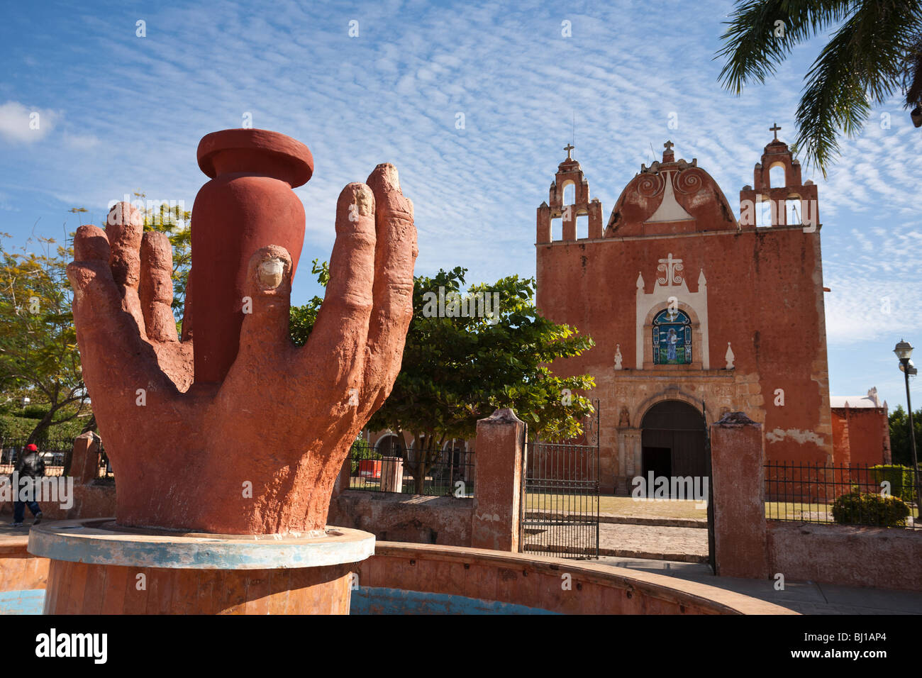 Hands of the potter in red clay frame a view of Ticul's main church. The red hands echo the