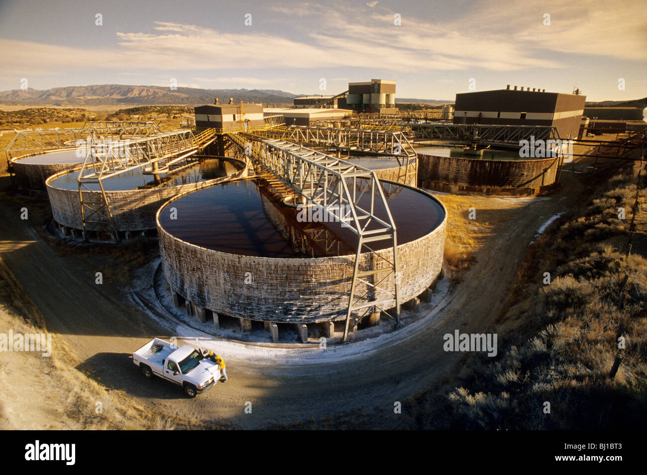 mine workers with pickup truck in front of large storage tanks at a uranium mine Stock Photo