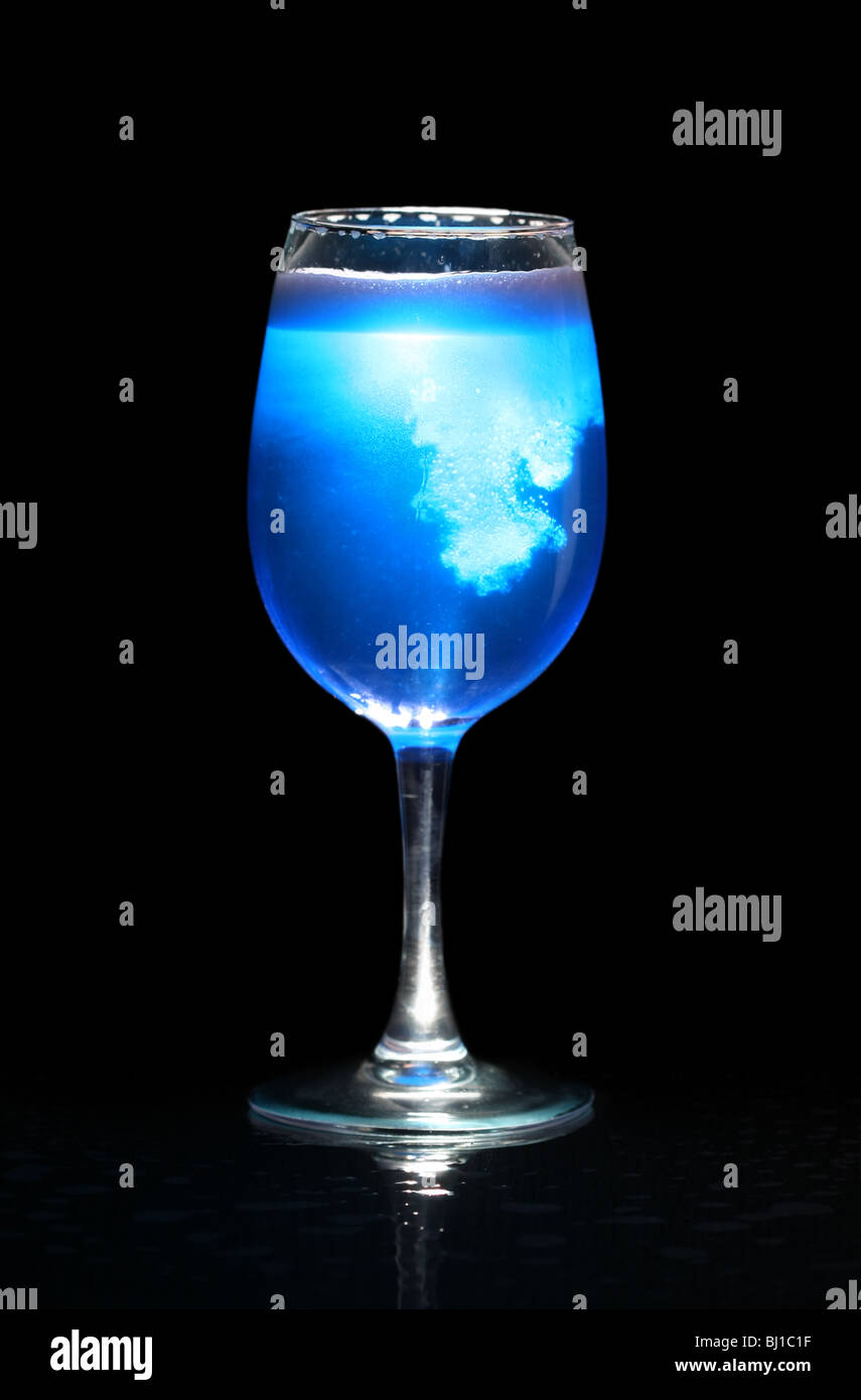 Glass with blue splashing beverage isolated on black Stock Photo