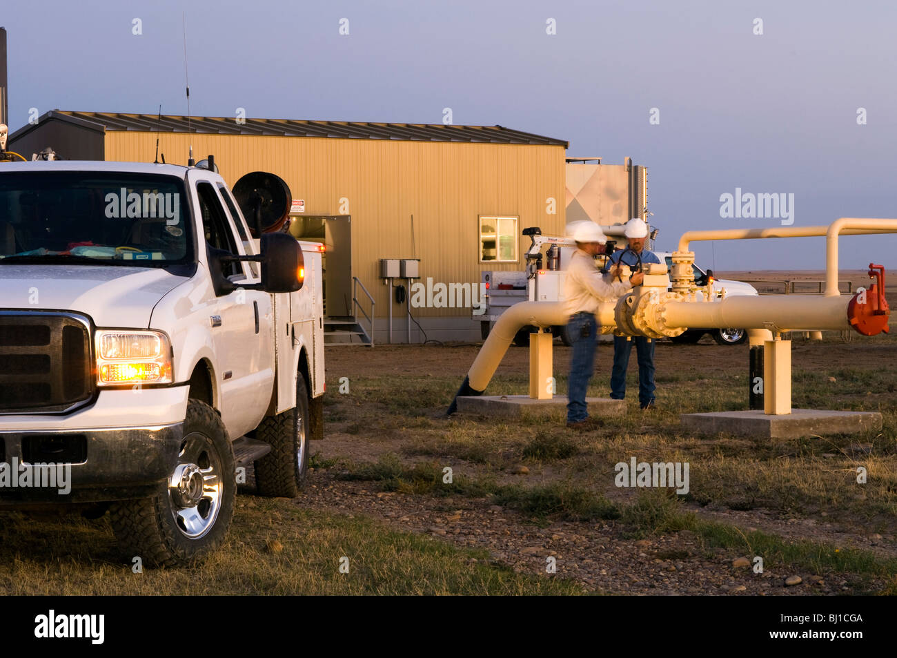 utility workers around a valve at a natural gas substation with a truck