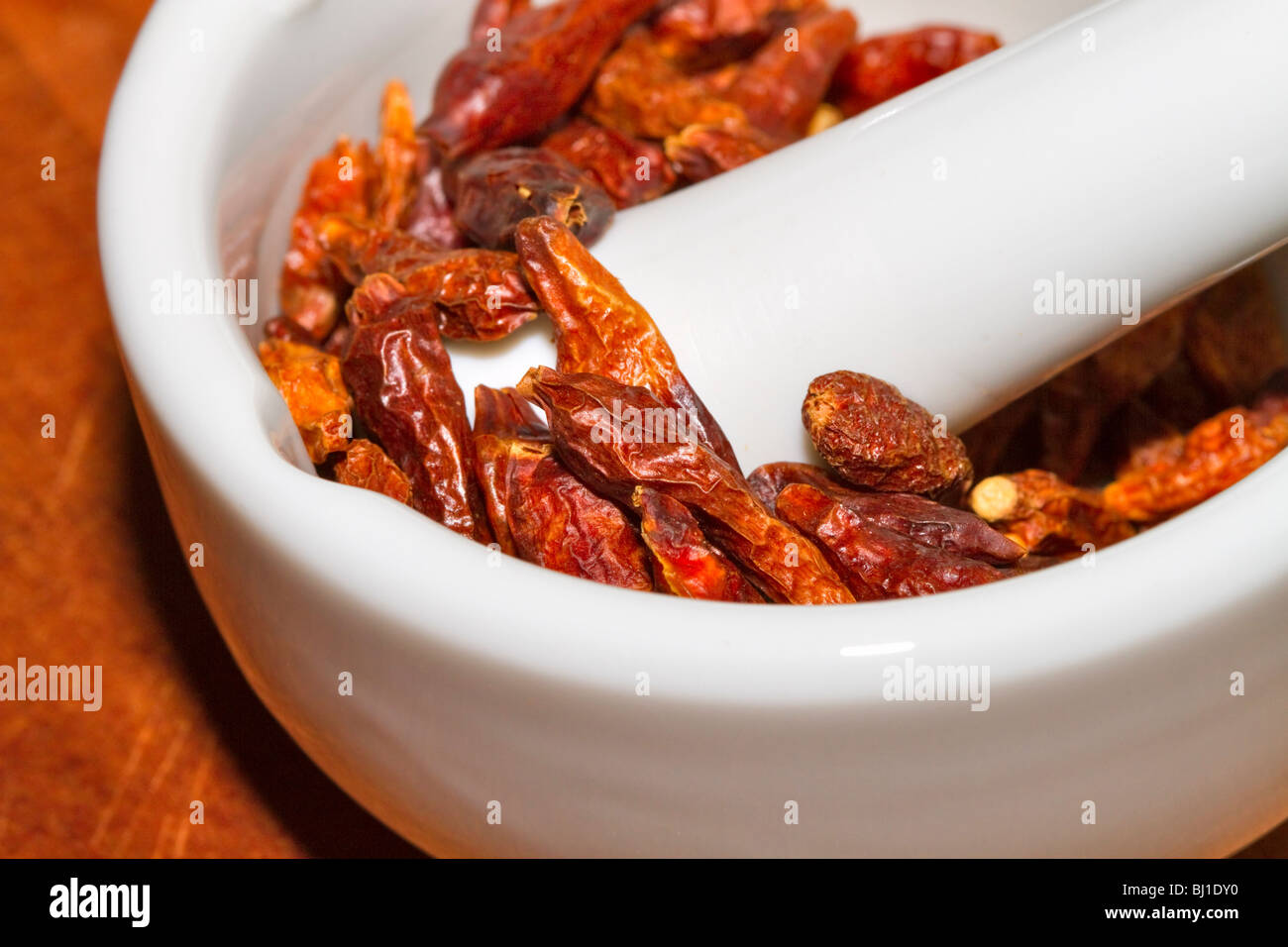 Dried whole cayenne peppers in a mortar and pestle Stock Photo