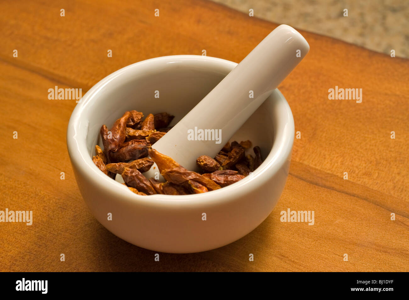 Dried whole cayenne peppers in a mortar and pestle Stock Photo