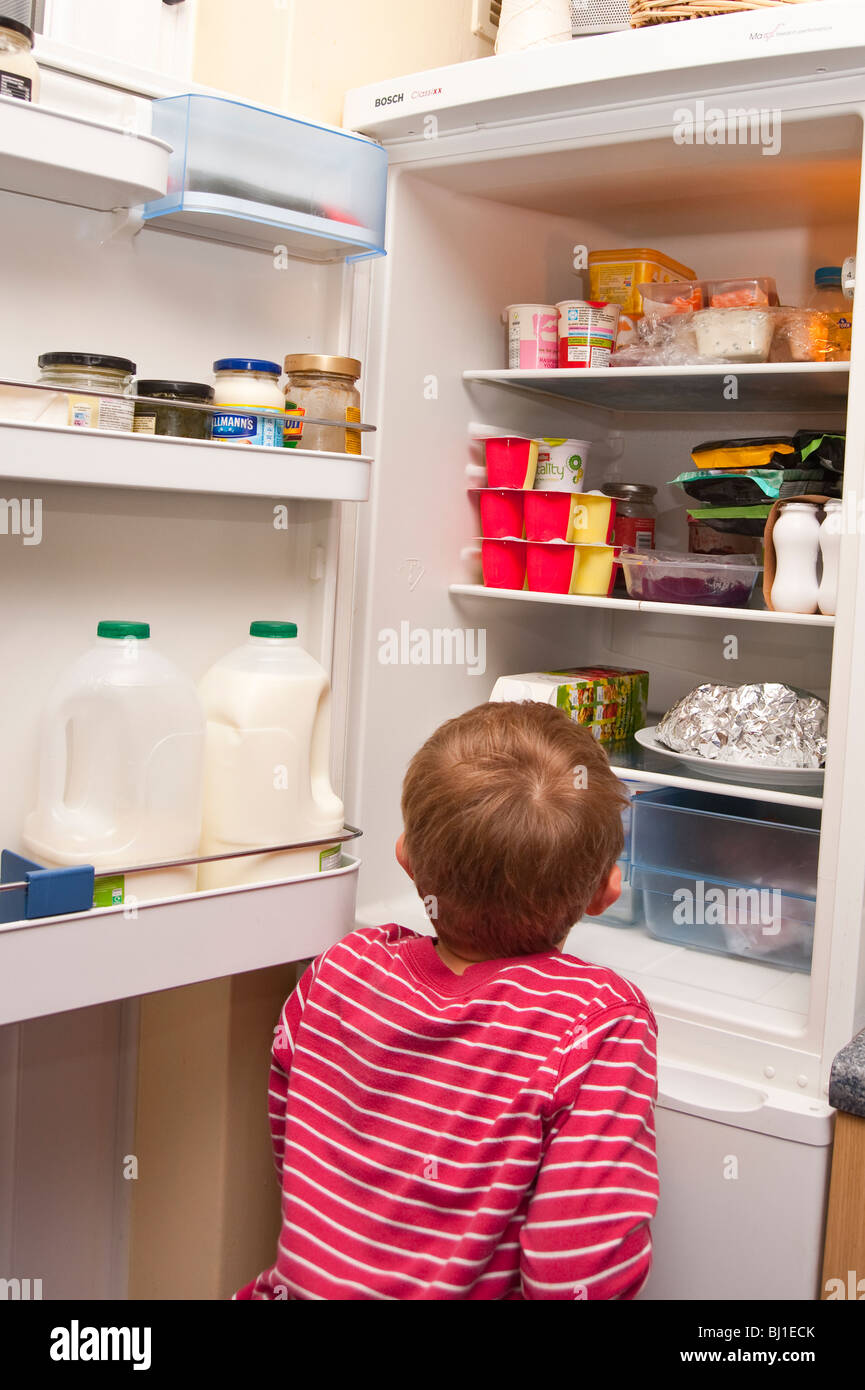 A MODEL RELEASED picture of a 6 year old boy raiding the fridge in the uk Stock Photo