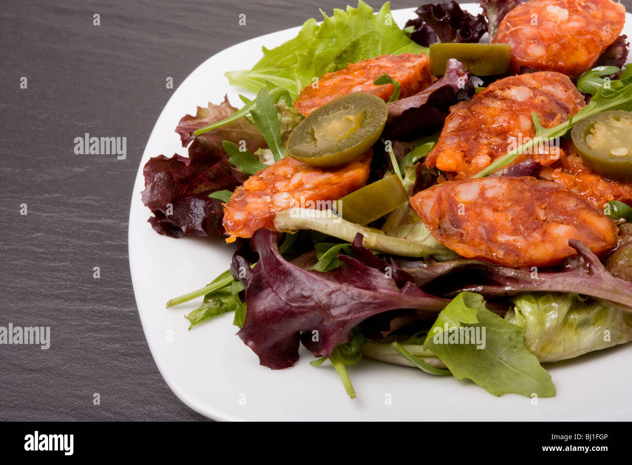 Spicy Mediterranean Salad of chorizo sausage with jalapeño chilli's and herby salad leafs Stock