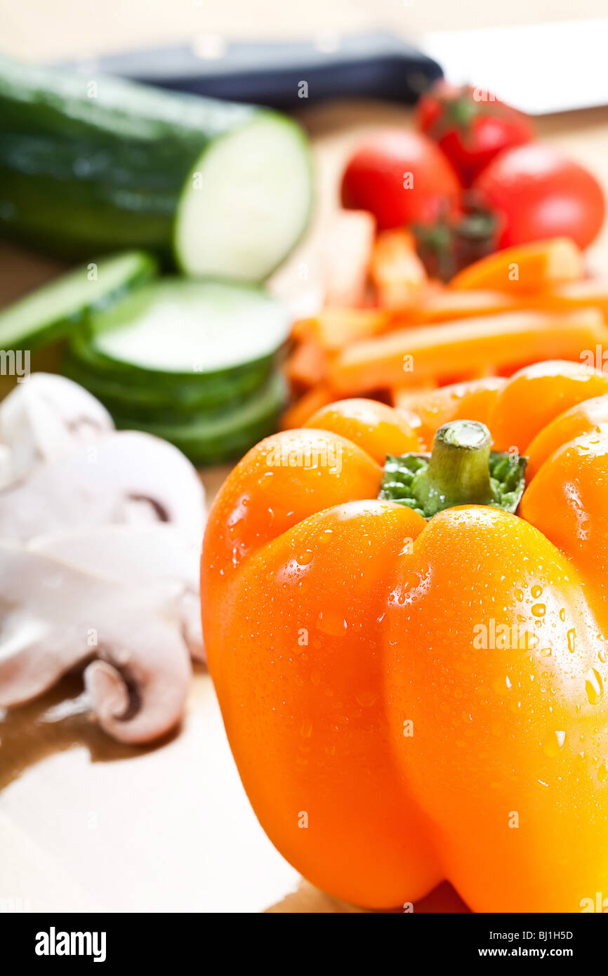 Selection of fine veg on a chopping board with a knife in the back. Stock Photo