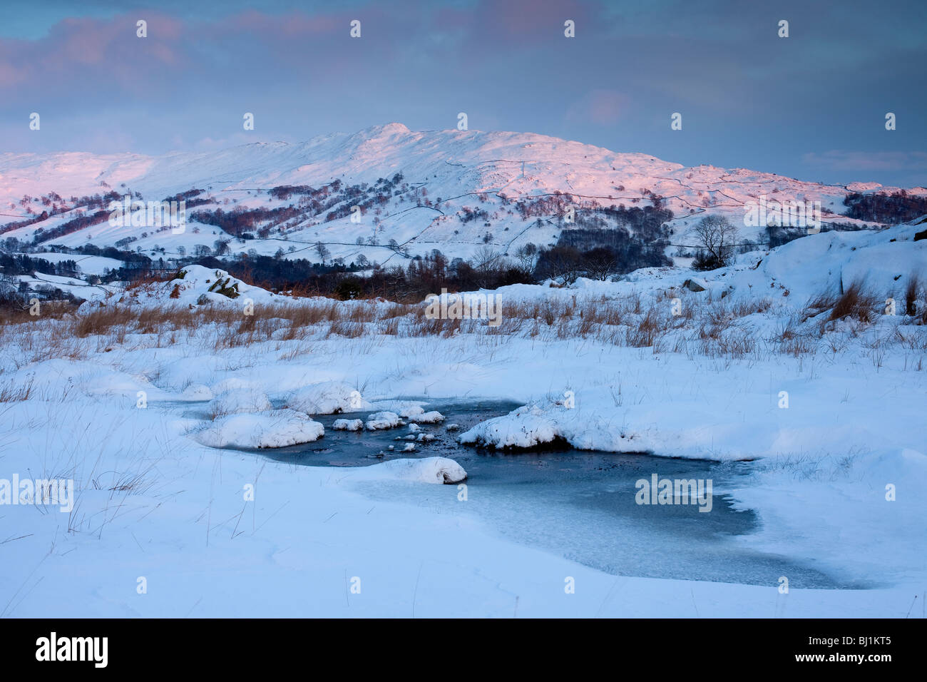 Wansfell illuminated by the setting sun in deep snow taken from Loughrigg fell near Ambleside. Stock Photo