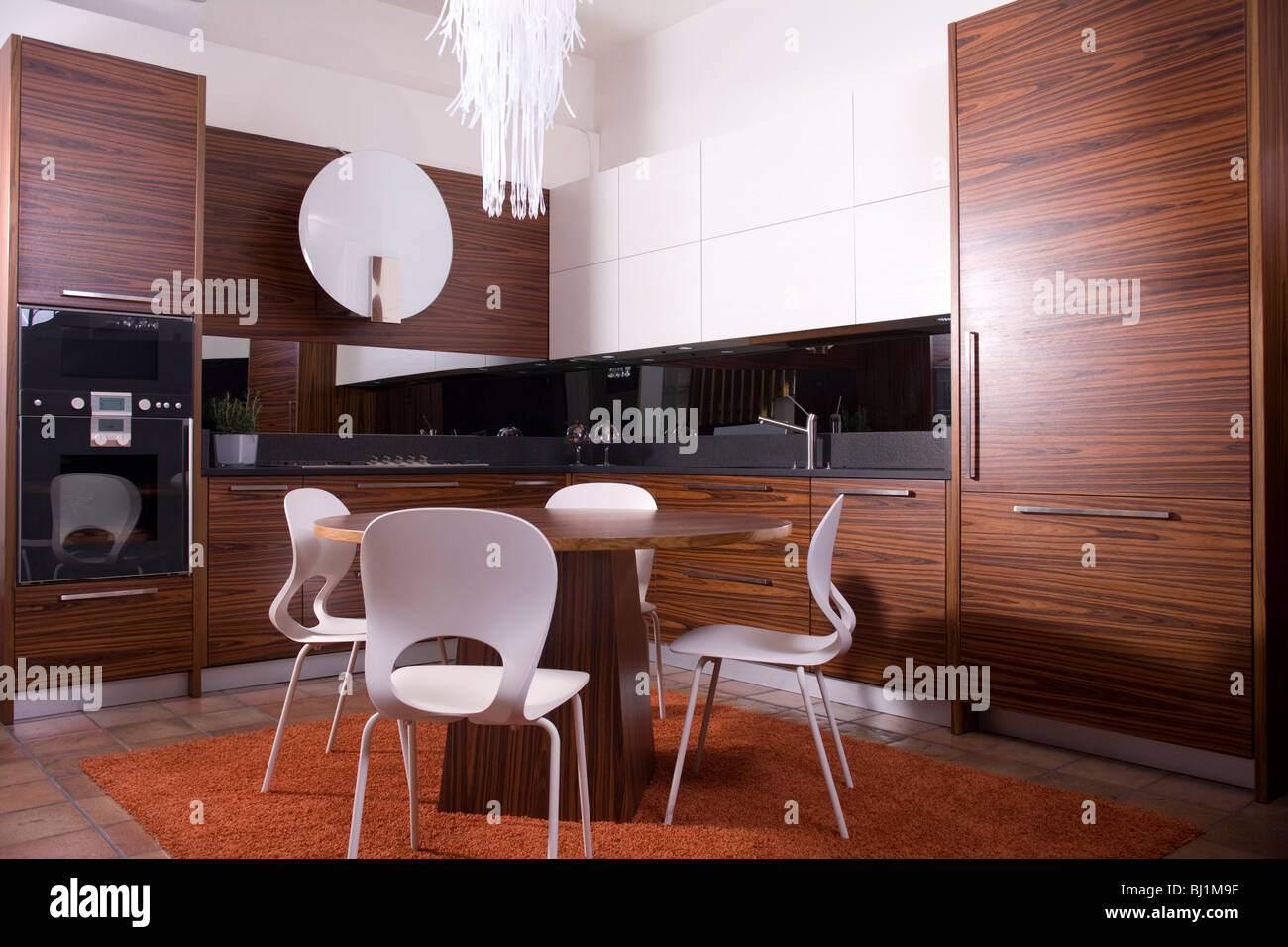 Modern kitchen with white and dark wood cabinets, chairs and table ...