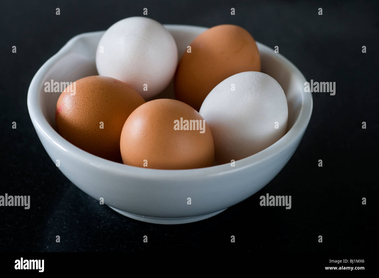 A bowl of eggs on a black kitchen work surface Stock Photo