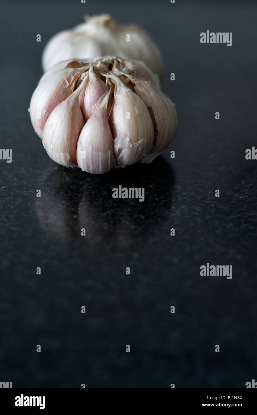 Garlic on a black kitchen work surface Stock Photo