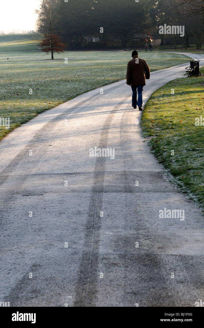 man walking on a frosty frost covered winding path in the castle park kilkenny ireland Stock Photo