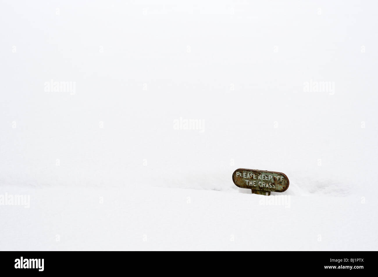 Snow covered lawn, with 'Keep of grass' warning board Stock Photo