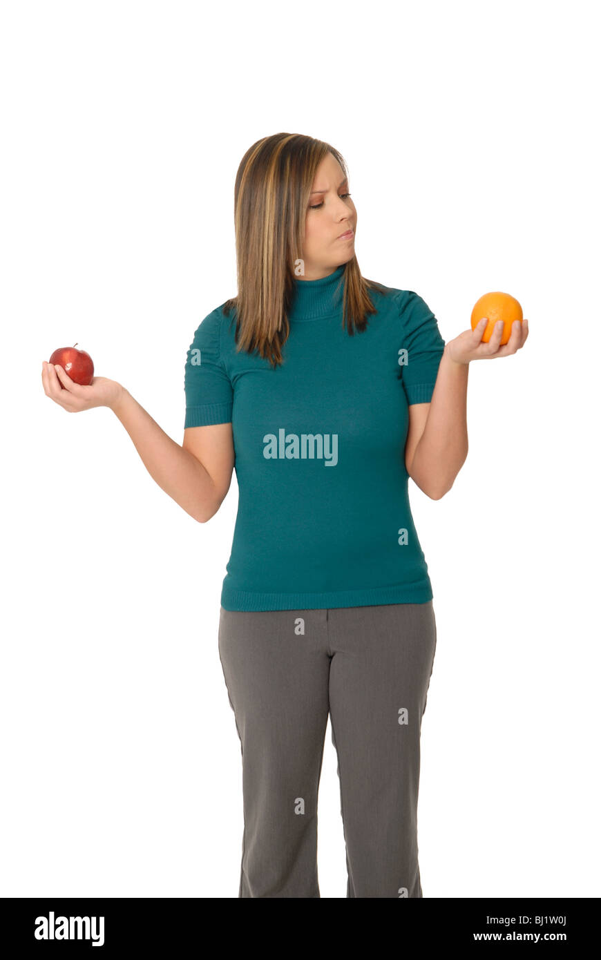 A young woman comparing an apple and an orange: "comparing apples to oranges". Stock Photo