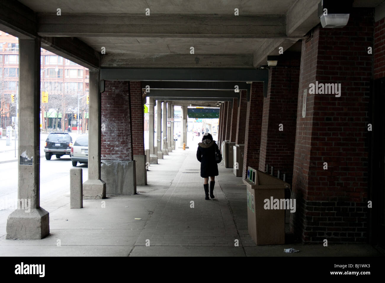 woman alone walking lonely under bridge dark Stock Photo