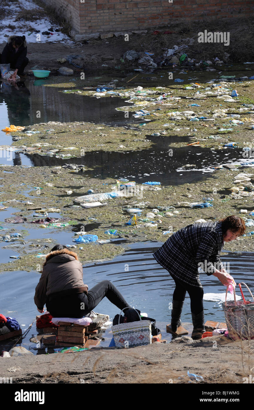 Women washing clothes in a polluted pond in a village in Hebei province, China. 02-Mar-2010 Stock Photo