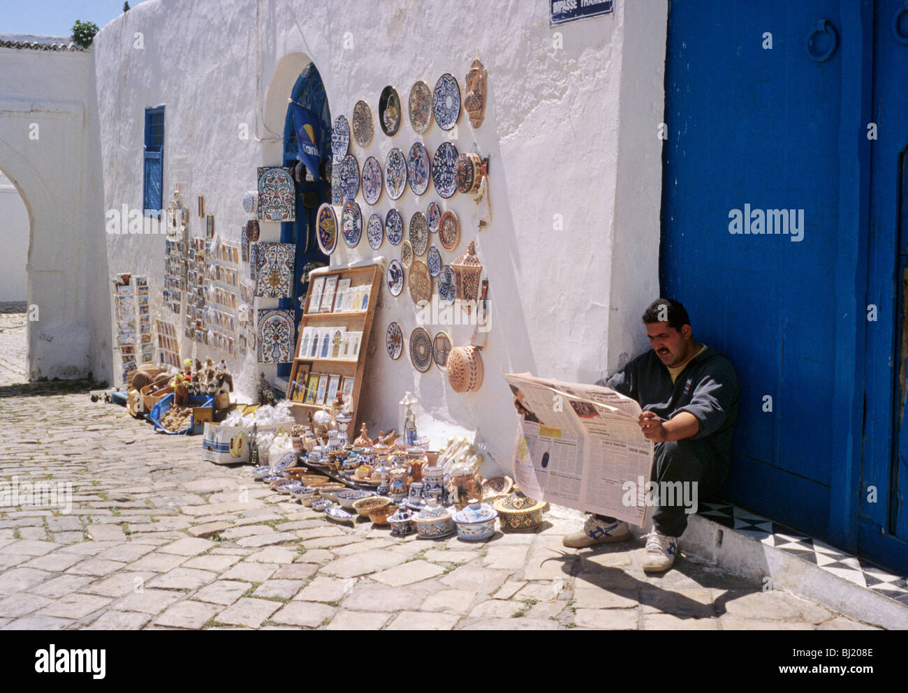 Man Reading Newspaper Beside Traditional Handicrafts Man Reading Newspaper Beside Traditional Handicrafts