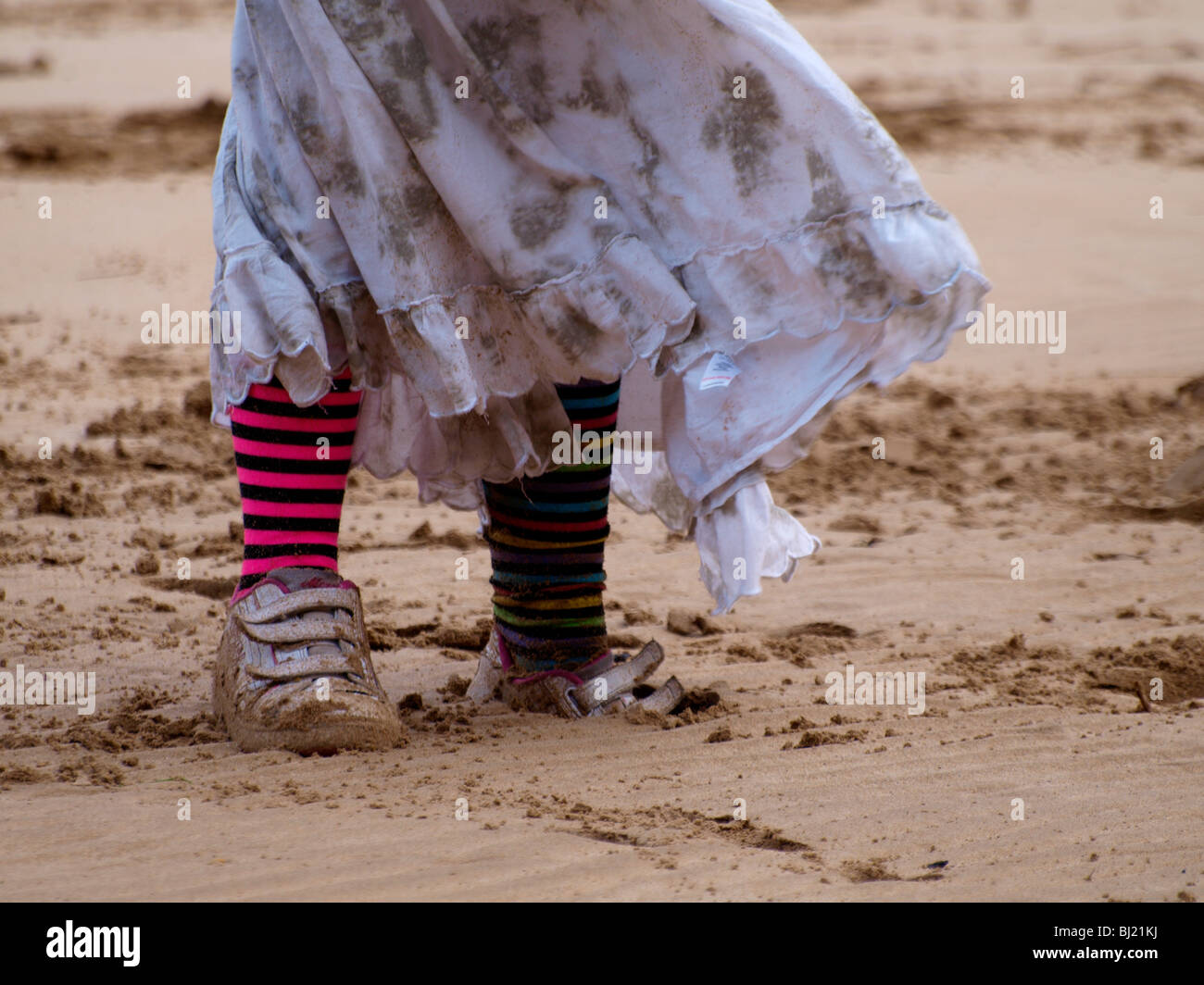 Legs of a young girl wearing stripy socks on the beach Stock Photo