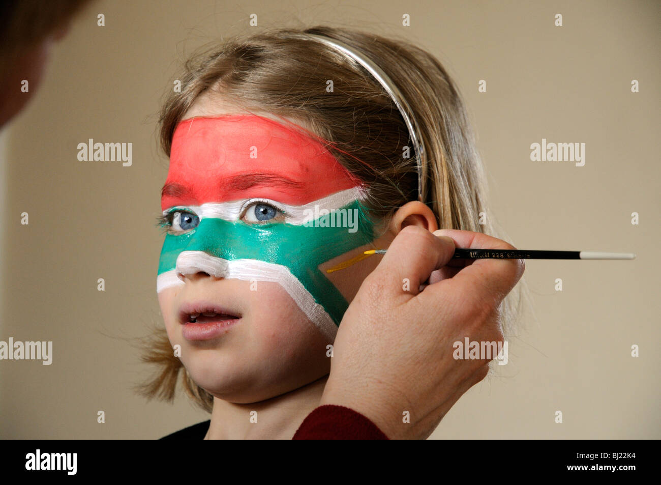 Little girl having her face painted with the national flag of South Africa Stock Photo