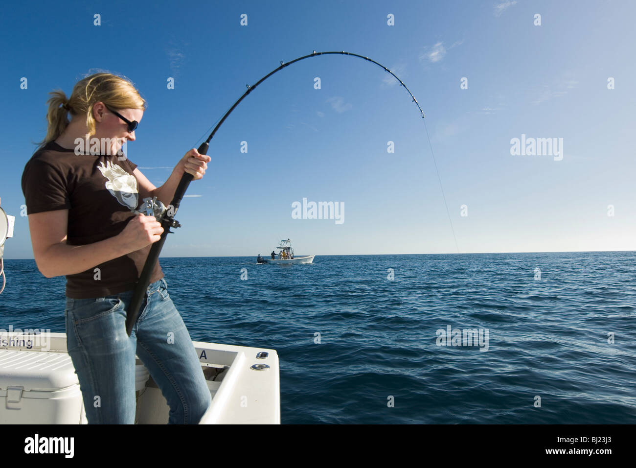 Woman fishing from a boat Stock Photo