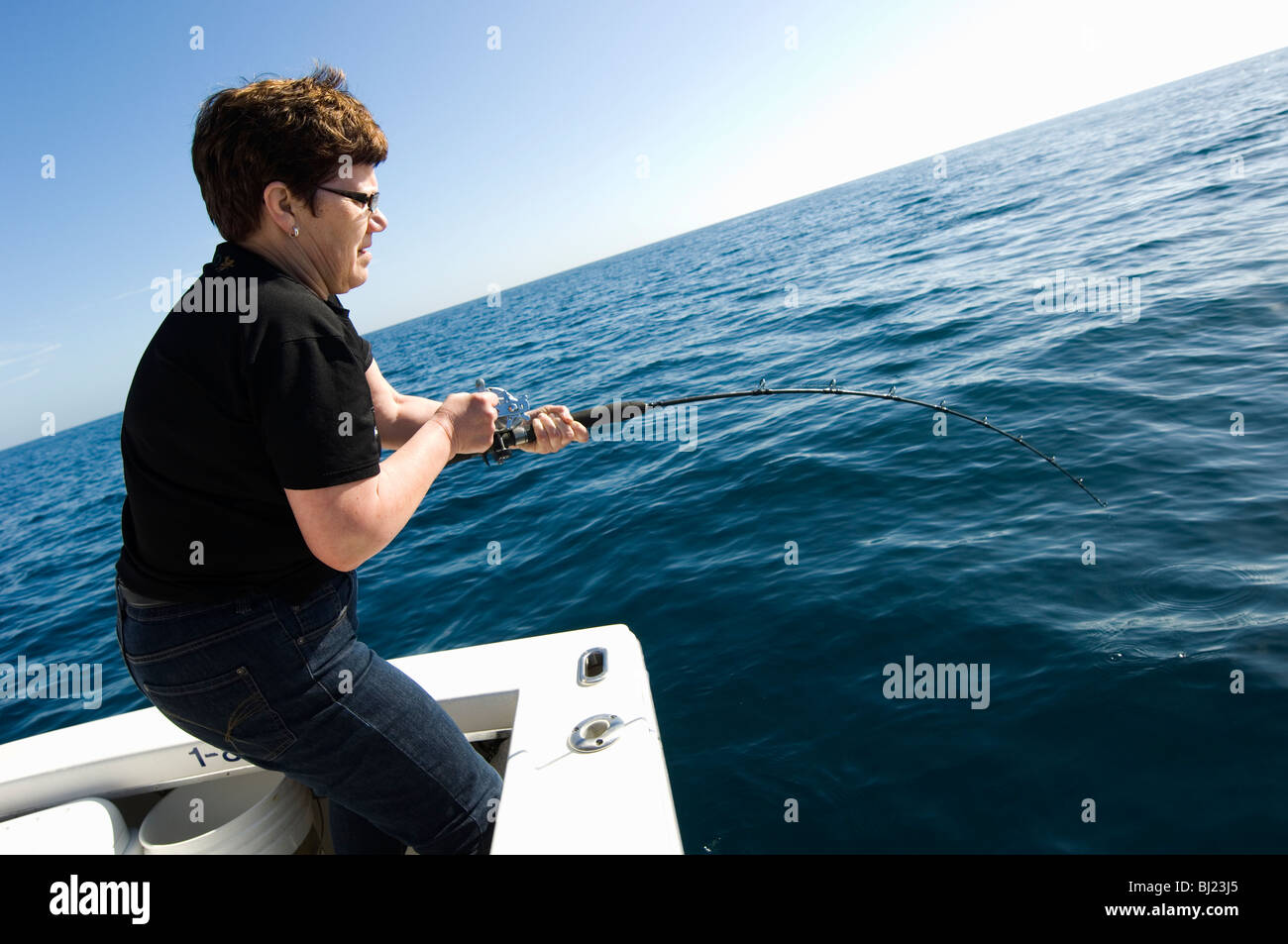 Woman fishing from a boat Stock Photo