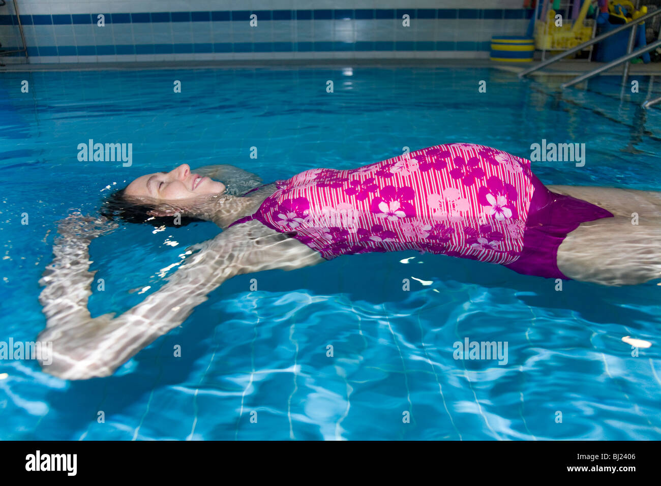 Pregnant woman swim / swimming / swims in a swimming pool. UK Stock