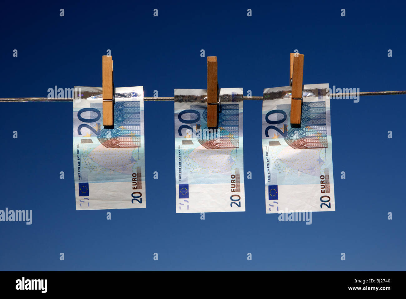 three twenty euro banknotes hanging on a washing line with blue sky Stock Photo