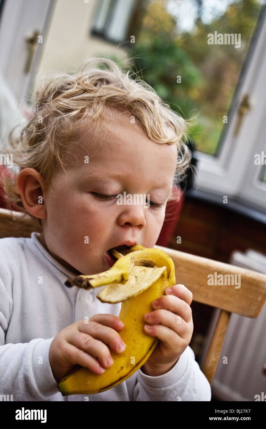 Toddler eating a banana Stock Photo - Alamy