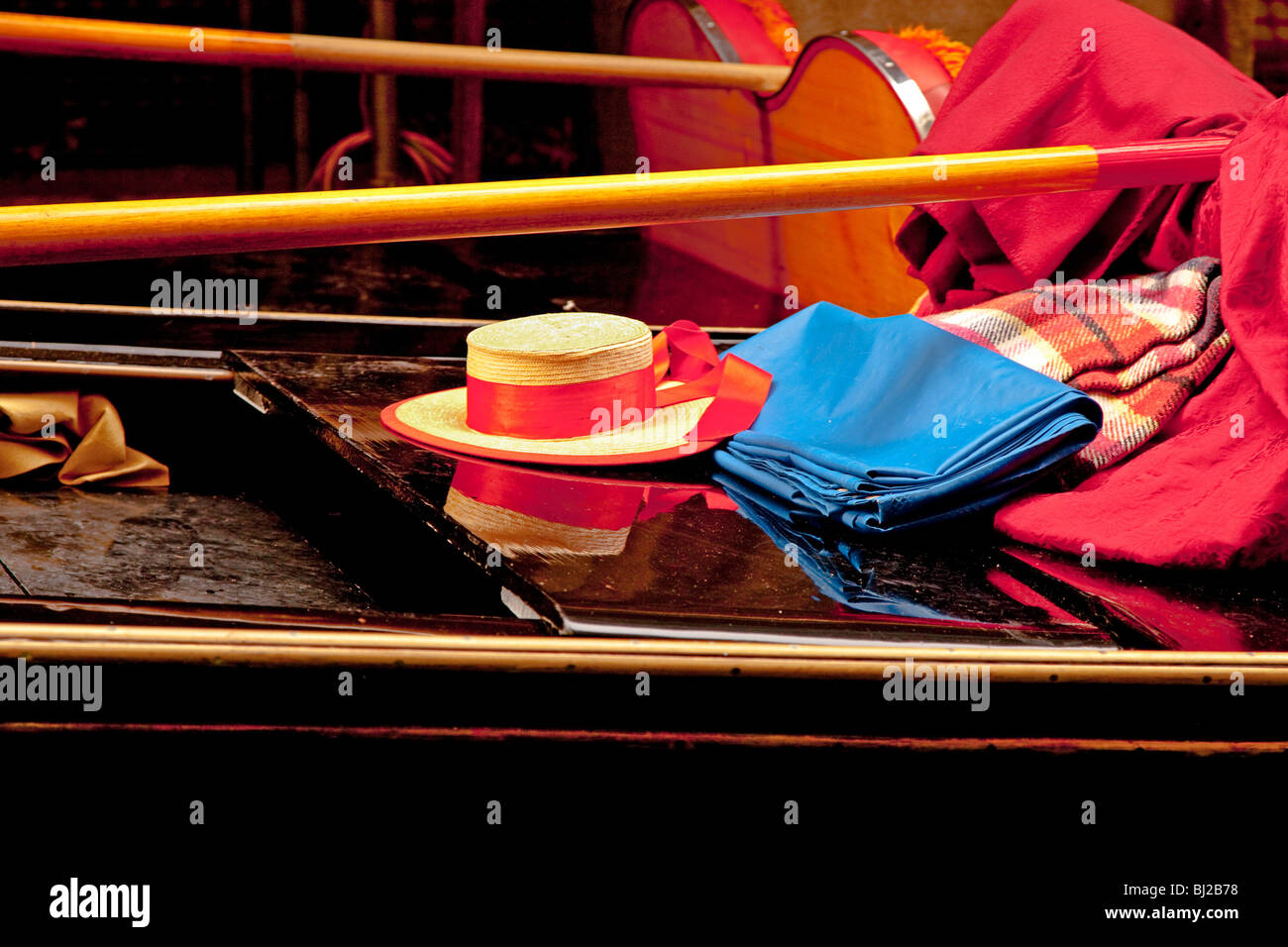 Bright colours of a Gondolier's hat , his oar and blankets on his highly polished Gondola Stock Photo