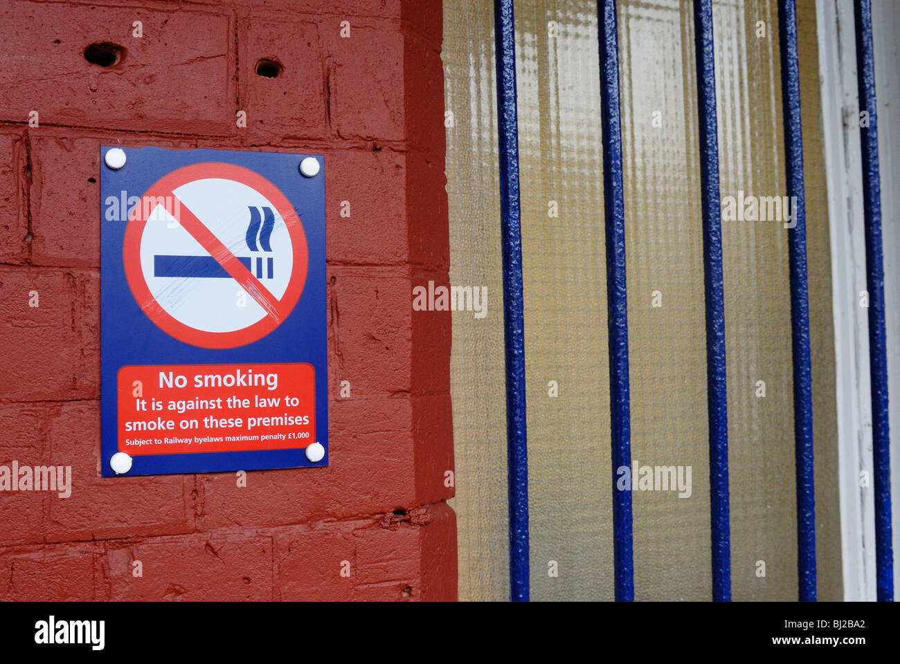 No smoking sign on railway station stating it is illegal. Juxtapositioned next to a barred window Stock Photo