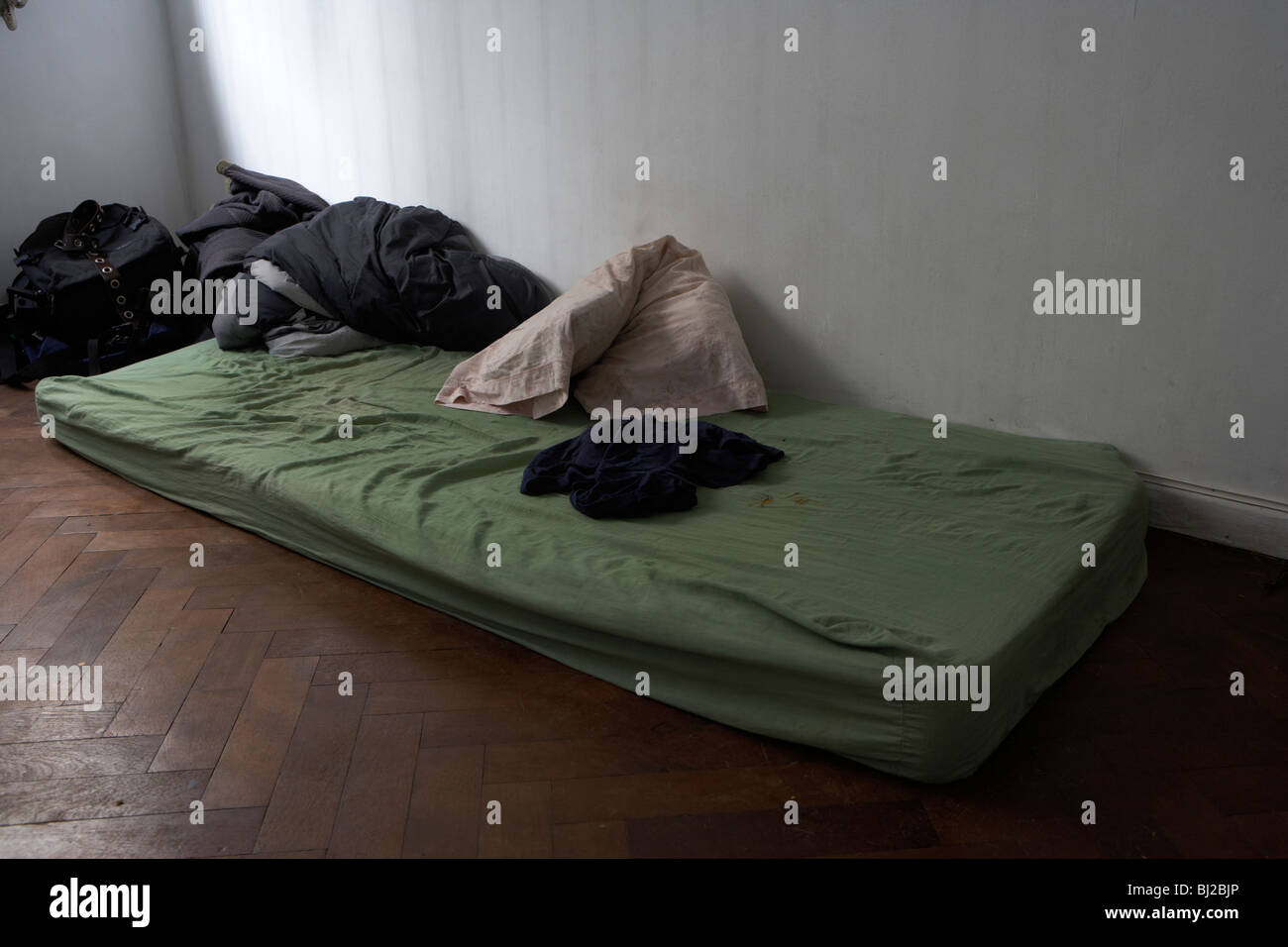 old dirty mattress lying on the floor in a bedroom for someone sleeping on the floor due to the housing crisis Stock Photo