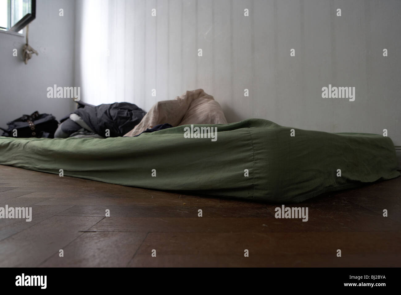 old dirty mattress lying on the floor in the corner of a bedroom Stock