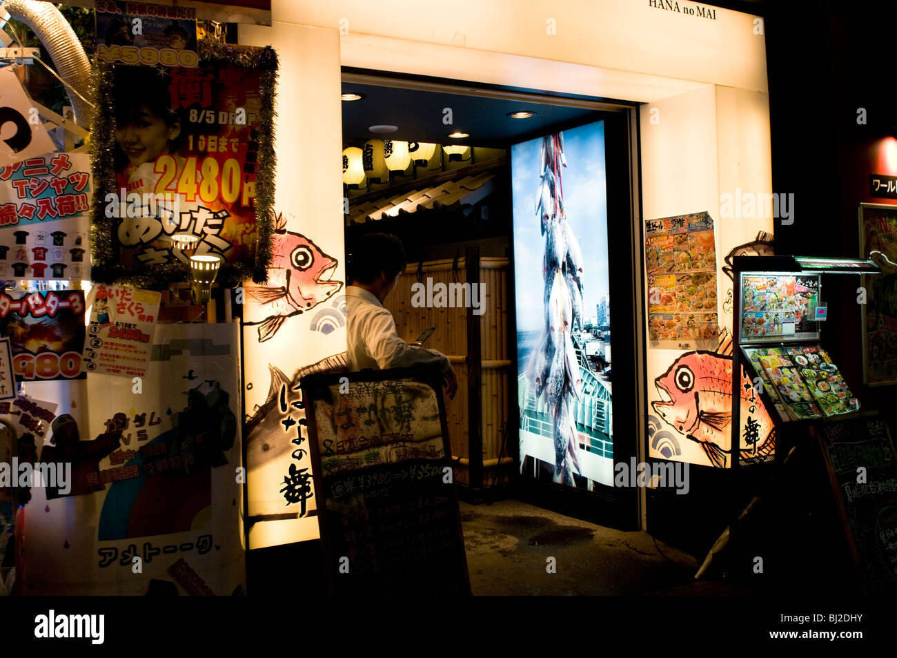 Salary man operating a cell phone in front of a Japanese bar (Izakaya), Tokyo-Shinjuku. Stock Photo