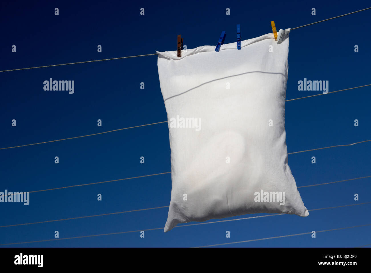 single pillow hanging on a washing line with blue sky Stock Photo