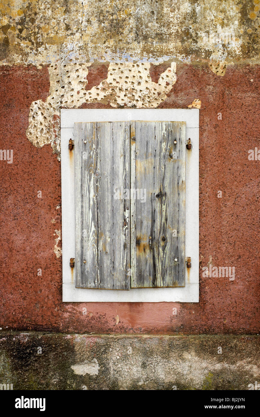 Rusty closed iron window with white border made of sotne. Wall has nice read texture. Stock Photo