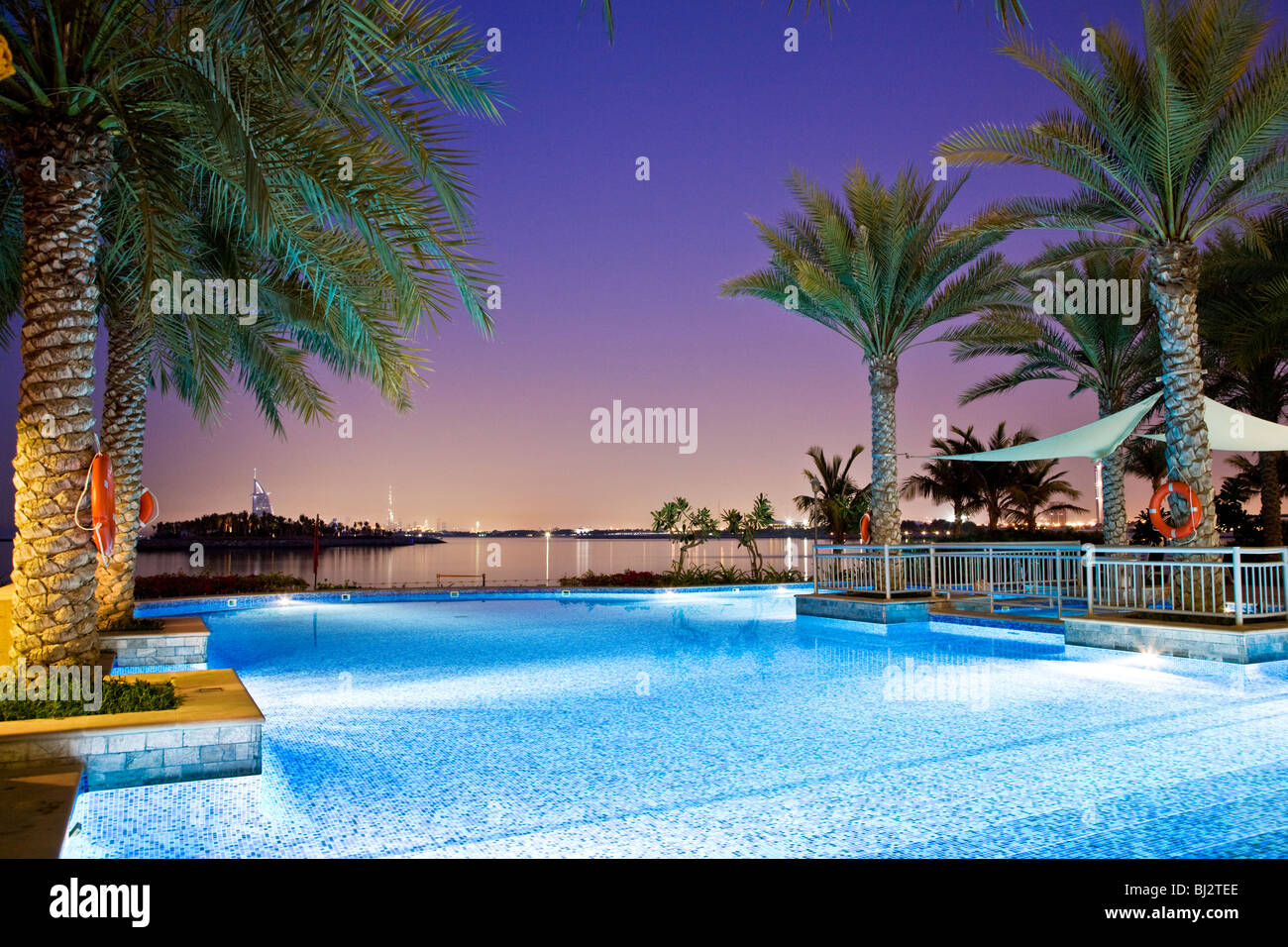 Swimming pool of a beach club on Palm Island Jumeirah in Dubai with the Burj al Arab and Burj Khalifa visible in the distance. Stock Photo