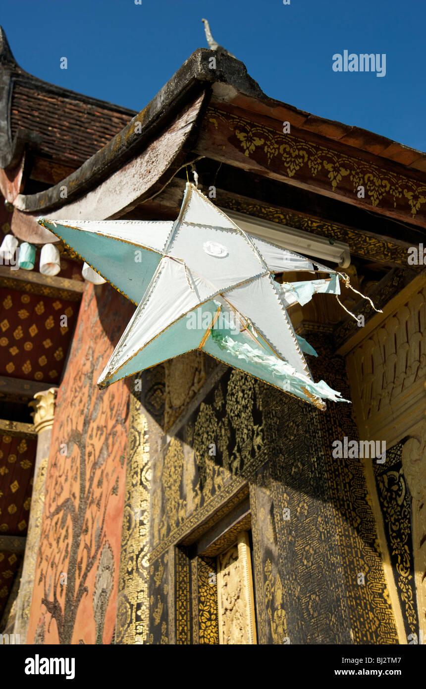 A paper lantern hangs from the eves of the tiled roof of the temple of Wat Xiang Thong in Luang Prabang Laos Stock Photo