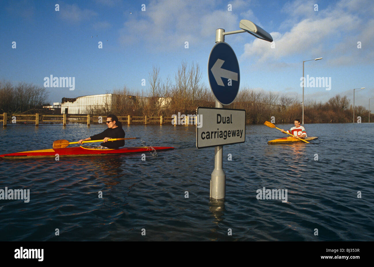 After heavy rain and the subsequent flooding, two lone canoeists paddle down the centre of the A27 near Chichester Stock Photo