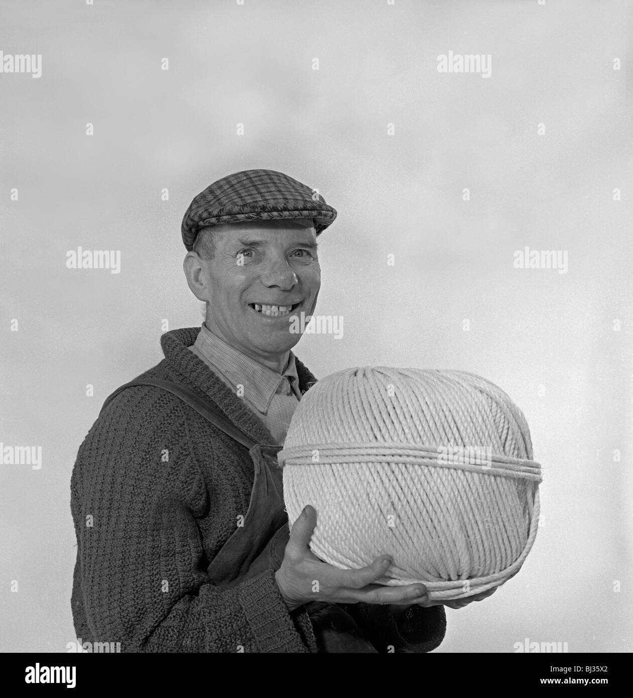 Yorkshireman wearing a flat cap and holding a large ball of twine, 1968. Artist Michael Walters