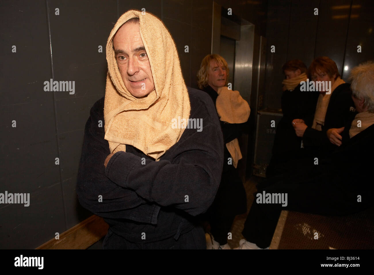 Guitarist Francis Rossi of the British rock and roll band Status Quo is wrapped in towels immediately after coming off stage Stock Photo